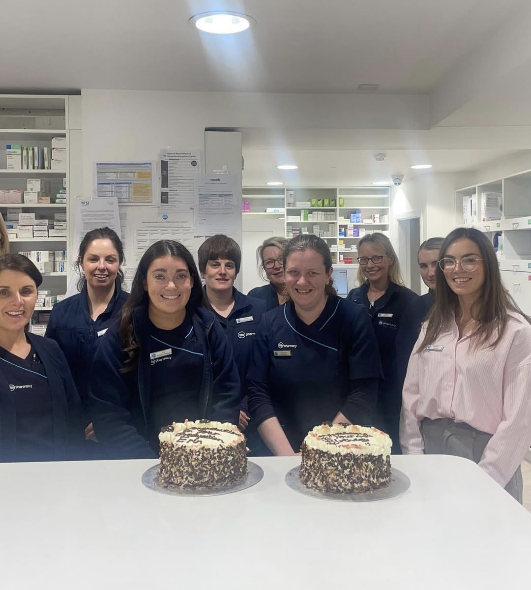 The Reens Life Pharmacy team gathered behind two celebration cakes